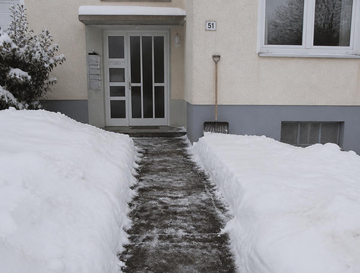 Geräumter Gehweg am Eingang eines Wohnhauses im Winter